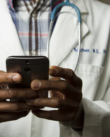 Clinician in a white coat using a smartphone