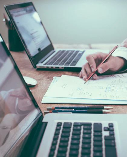 Professional at a desk reviewing documents beside a laptop